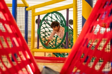 طفل عربي يلعب في منطقة ألعاب داخلية ملونة