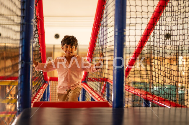 Young Arab Boy Playing on Indoor Playground Bridge Area