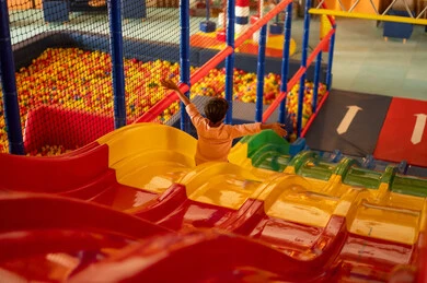 Saudi Boy on Colorful Slide in Indoor Playground