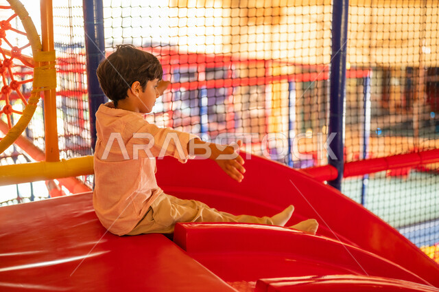 Arab Boy Playing on Indoor Red Slide