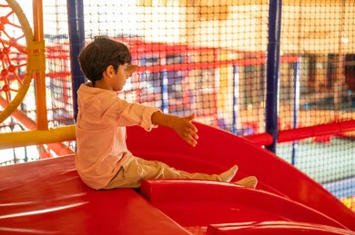 Arab Boy Playing on Indoor Red Slide