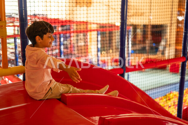 Arab Boy on Red Slide in Indoor Playground