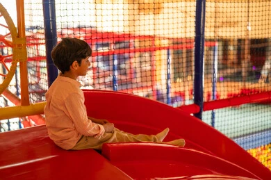 طفل سعودي يجلس على منزلق أحمر في منطقة ألعاب