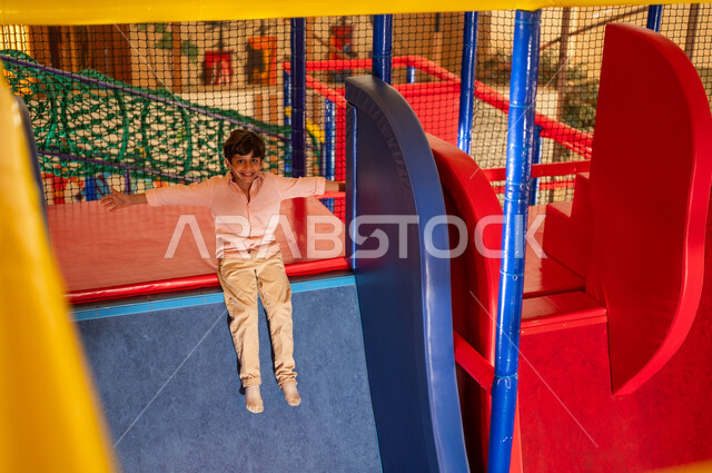 Arab Boy Sliding in Indoor Playground