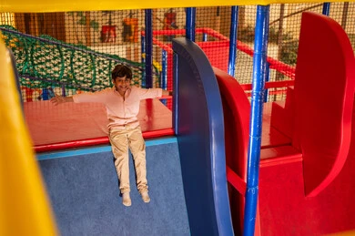 Arab Boy Sliding in Indoor Playground