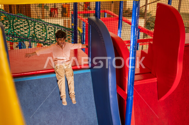 Saudi Boy Playing on Slide in Indoor Recreation Center