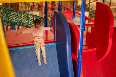 Saudi Boy Playing on Slide in Indoor Recreation Center