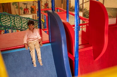 Saudi Boy Sitting on Slide in Indoor Playground