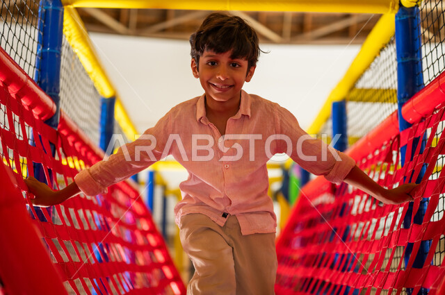 Saudi Boy Playing on Rope Bridge at Indoor Playground