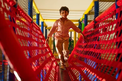 طفل سعودي يسير على جسر حبال في منطقة ألعاب