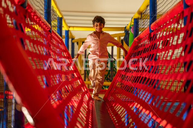 طفل عربي يوازن نفسه في منطقة ألعاب مغلقة