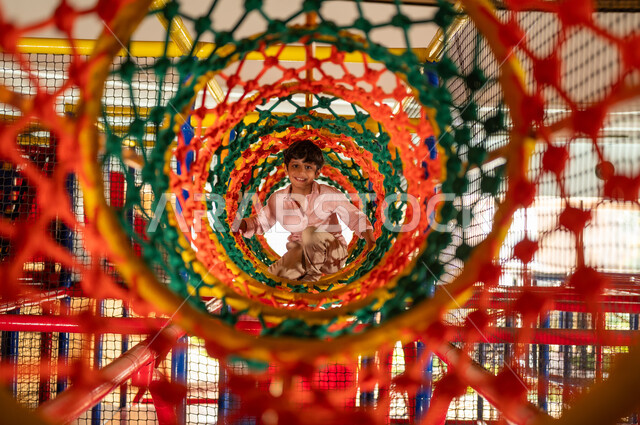 Arab Boy Playing in Indoor Rope Tunnel Playground