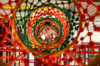 طفل عربي يلعب في نفق الحبال في منطقة ألعاب