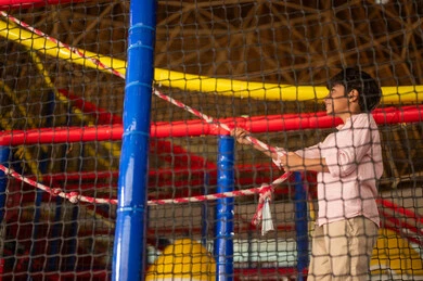 Arab Boy Climbing Rope Course in Indoor Playground