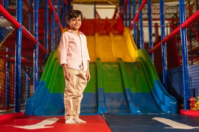 Arab Boy in Indoor Playground with Colorful Slide