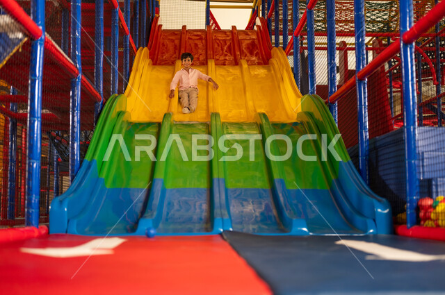 Saudi Boy Playing on Indoor Playground Slide