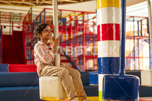Arab Boy Playing in Indoor Playground Carousel