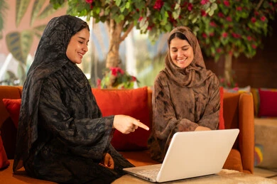 سيدات عربيات يستخدمن جهاز كمبيوتر محمول بالعباءة