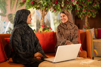 Arab Women in Abayas Using Laptop on Sofa