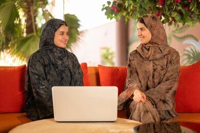 امرأتان خليجيتان بالعباءة تستخدمان اللابتوب في الخارج