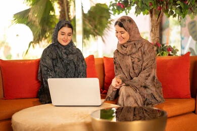 Arab Women in Abayas Using Laptop in Indoor Garden