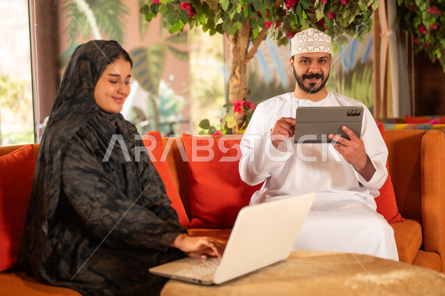 زوجان عمانيان يستخدمان اللابتوب والجهاز اللوحي
