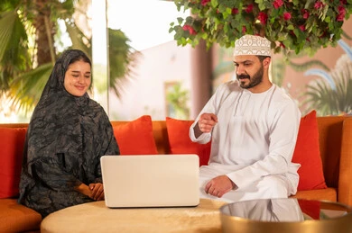 رجل وامرأة من عمان يستخدمان حاسوب محمول