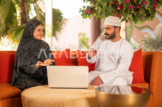 رجل وامرأة من عمان يستخدمان المحمول في مكتب