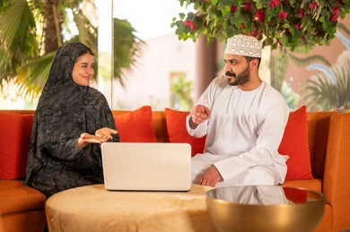 رجل وامرأة من عمان يستخدمان المحمول في مكتب