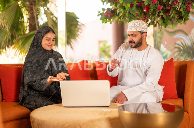 Omani Couple Using Laptop in Traditional Clothing