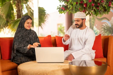 Omani Couple Using Laptop in Traditional Clothing