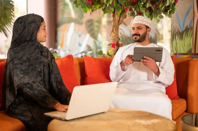 Omani Man and Woman Using Technology Indoors