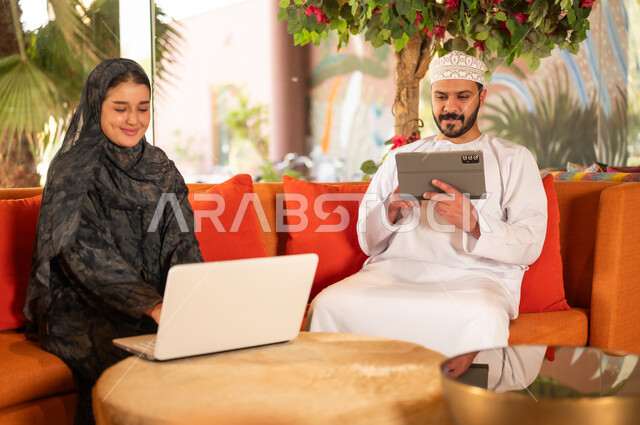 Omani Man and Woman Using Technology on Sofa