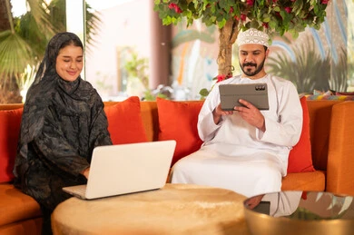 Omani Man and Woman Using Technology on Sofa