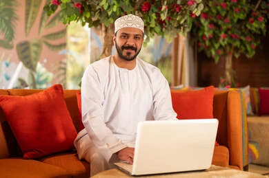 رجل عماني بالزي التقليدي يستخدم الحاسوب