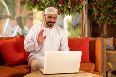 Omani Man Waving at Laptop in Traditional Dress