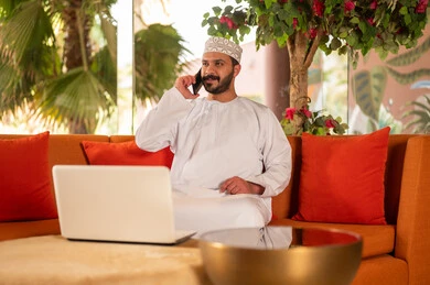 رجل عماني باللباس التقليدي يعمل على الكمبيوتر