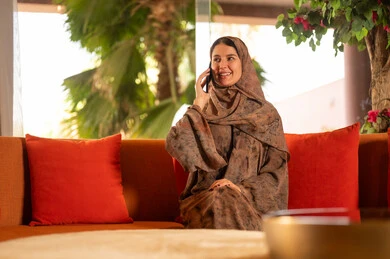 Smiling Arab Woman in Abaya Talking on Smartphone