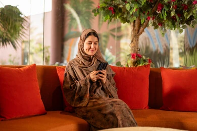 امرأة سعودية بالعباءة تستخدم الهاتف الذكي في الداخل