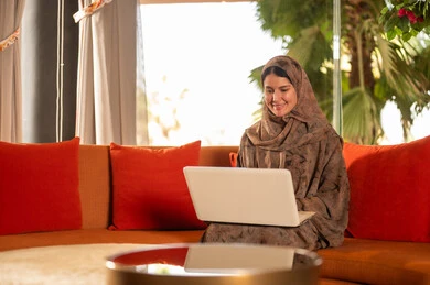 Saudi Woman in Abaya Using Laptop on Sofa