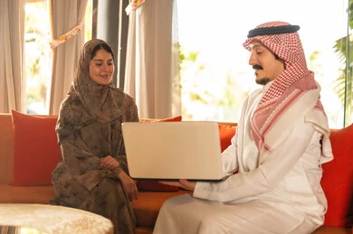 Saudi Man and Woman Using Laptop in Traditional Dress