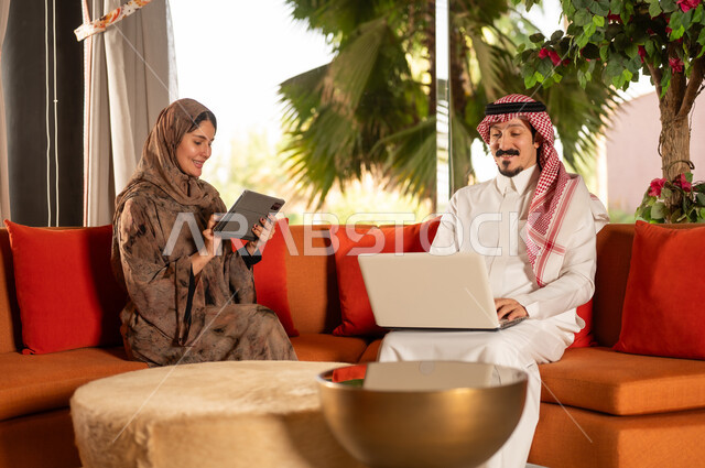 رجل وامرأة سعوديان يستخدمان الكمبيوتر المحمول والتابلت