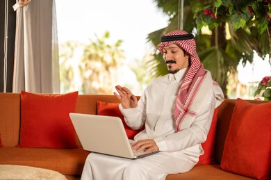 Saudi Man Using Laptop for Video Call Outdoors