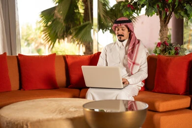 Saudi Man Using Laptop on Orange Couch