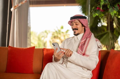 Saudi Man in Traditional Thobe Using Smartphone