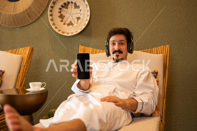 Saudi Man in Bathrobe Using Smartphone at Spa