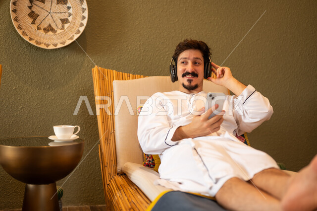 Arab Man in White Robe Relaxing with Headphones