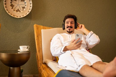 Arab Man in White Robe Relaxing with Headphones
