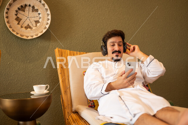 Arab Man in Bathrobe Using Smartphone and Headphones