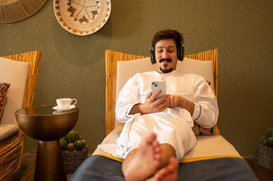 رجل يرتدي رداء حمام أبيض يستخدم الهاتف في السبا